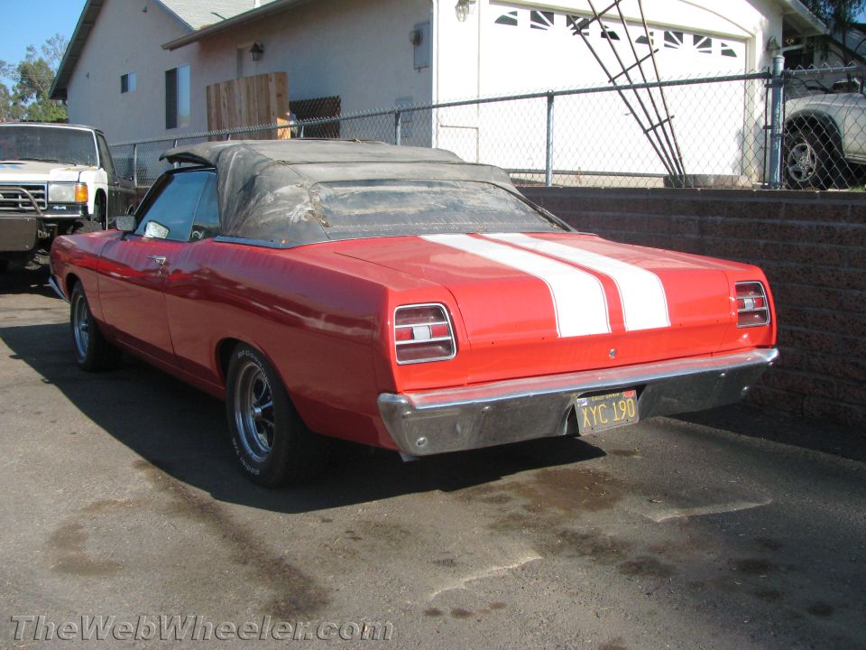 Rear view of a red convertible with white stripes, California plate, black top