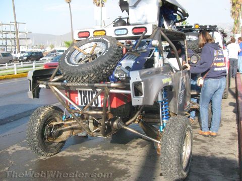 1990 Ford Bronco - Rear view of a tube-frame race buggy numbered 1803 carrying two spare tires, with blue coilover shocks and a rear light bar.