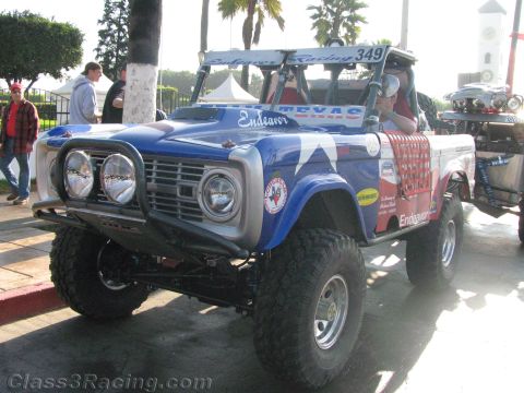 1990 Ford Bronco - Front three-quarter view of a lifted early Ford Bronco off-road racer with twin round headlights, brush guard and number 349.