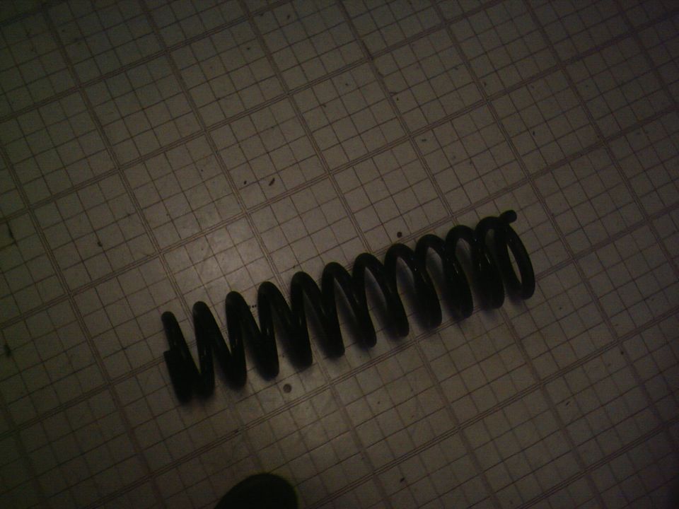 Black coil spring on a grid floor