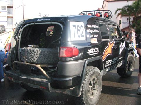 1990 Ford Bronco - Rear three-quarter view of a black Toyota FJ Cruiser off-road racer #762 with Alpinestars livery and a rear-mounted spare tire.