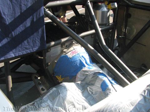 1990 Ford Bronco - close-up inside an off-road race car showing the tubular roll cage and a taped blue and silver wrapped component.