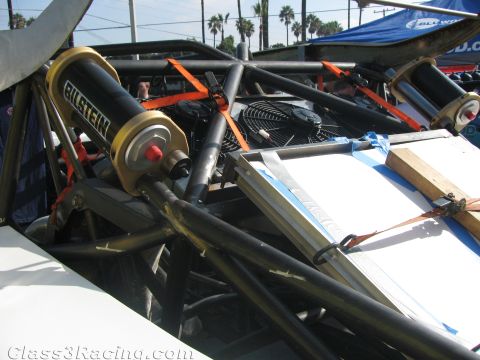 1990 Ford Bronco - close-up of a gold Bilstein shock absorber and a cooling fan mounted within the tubular chassis of an off-road race vehicle.