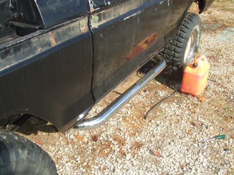 1979 Ford Bronco - Chrome step bars are visible on the side of a black SUV, with an orange gas can and a screwdriver on the ground.