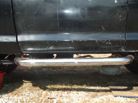 1979 Ford Bronco - Chrome step bars are installed below the doors of a black vehicle.