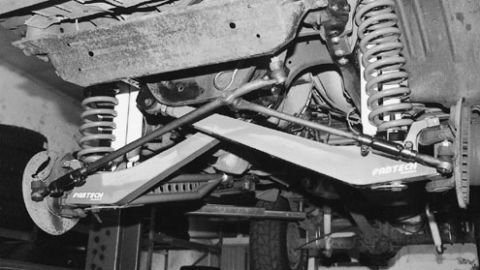 1984 Ford Bronco - Close-up view of a vehicle's suspension system, highlighting aftermarket parts.