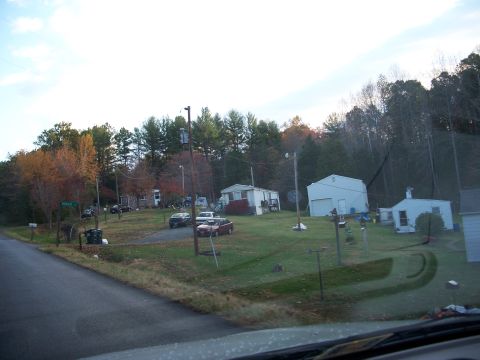 1971 Ford Ranchero - A collection of vehicles are visible in front of residential buildings and a wooded area.