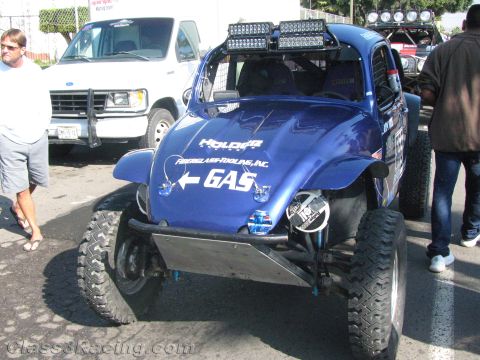 1990 Ford Bronco - blue Volkswagen-style Baja Bug off-road racer with a roof light bar and a fuel arrow decal sits on pavement at an event.