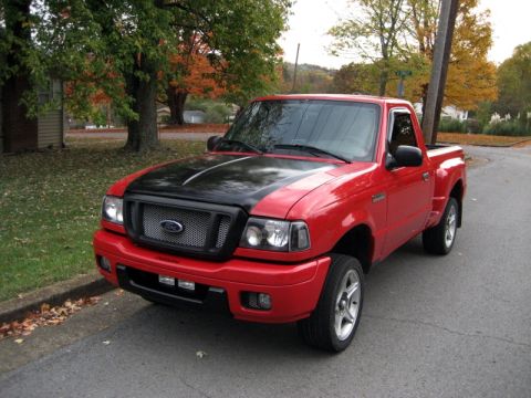 2004 Ford Ranger - A red 2004 Ford Ranger pickup truck with a black hood is parked on the side of a street.