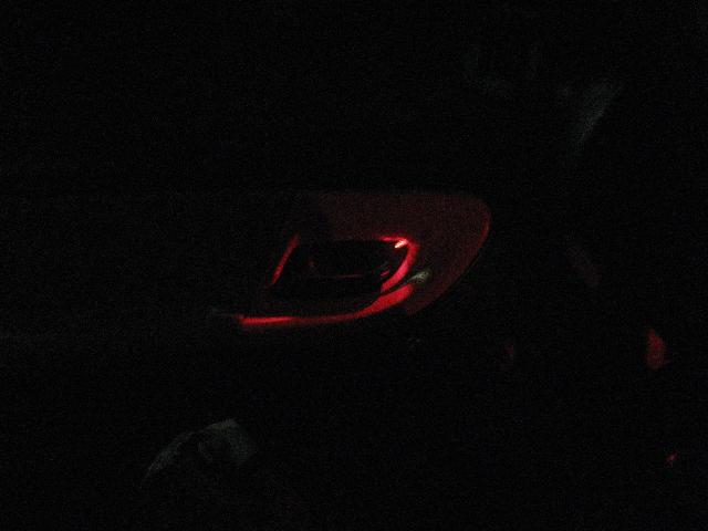 Dark interior with red ambient light illuminating a portion of the dashboard
