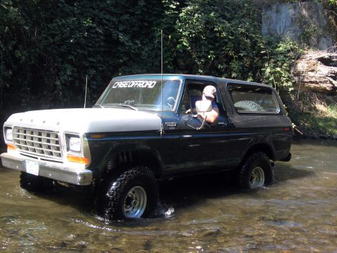 1979 Ford Bronco - A 1978 Ford Bronco navigates a stream, its front grille and two-tone paint clearly visible.