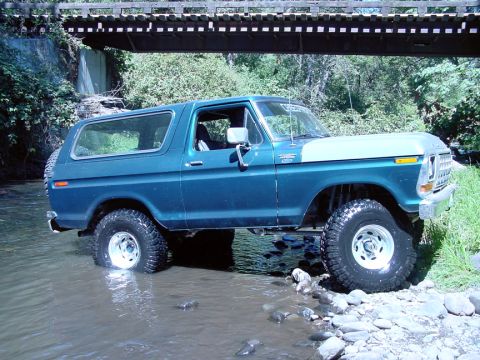 1979 Ford Bronco - A 1978 Ford Bronco navigates a rocky stream bed beneath a wooden overpass.