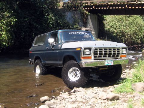 1979 Ford Bronco - Ford Bronco navigates a rocky stream bed, with 'CAGEOFFROAD' decal on windshield.