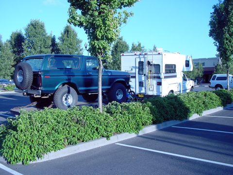 1979 Ford Bronco - A green 1978 Ford Bronco is parked next to a white camper in a parking lot.