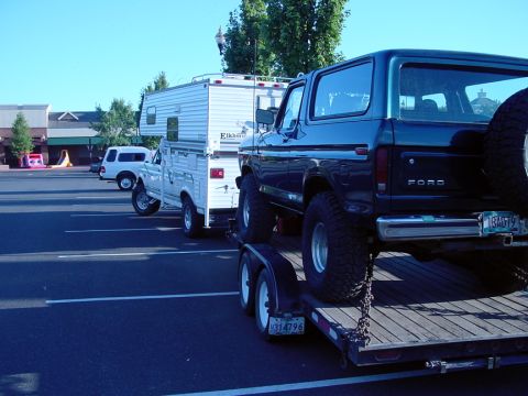 1979 Ford Bronco - A dark blue 1979 Ford Bronco is seen on a trailer, with a white truck and camper in the background.
