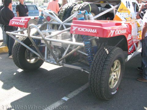 1990 Ford Bronco - Rear three-quarter view of a red Yokohama-sponsored tube-chassis off-road race truck showing the cage, coilovers and tires.