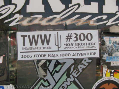 1990 Ford Bronco - Close-up of a decal reading TheWebWheeler.com #300 Moss Brothers, 2005 SCORE Baja 1000 Adventure, among other stickers.