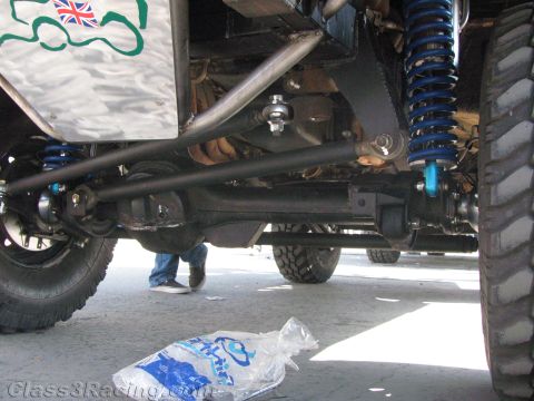 1990 Ford Bronco - Underside view of an off-road vehicle's front suspension with a solid axle, blue coil-over shocks and driveshaft.