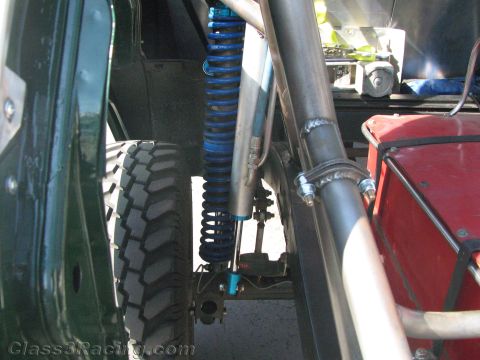1990 Ford Bronco - Close-up of an off-road vehicle's suspension with a blue coil-over shock, mud tire and tubular frame.