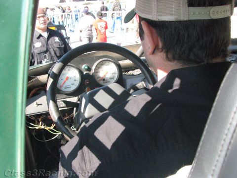 1990 Ford Bronco - View over a driver's shoulder showing a steering wheel and tach/speedo gauges inside a race vehicle.