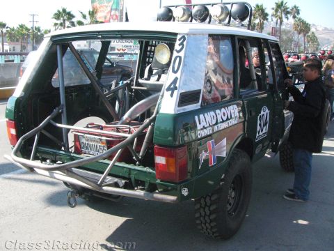 1990 Ford Bronco - Rear three-quarter view of a green Range Rover off-road racer numbered 304 with a tubular bumper and Land Rover graphics.