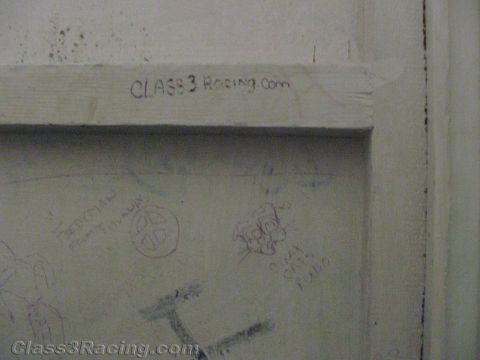 1990 Ford Bronco - pale-painted wooden door covered in faint pencil graffiti, with 'CLASS3 Racing.com' handwritten across the upper frame.