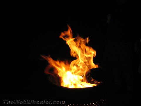 1990 Ford Bronco - Tall orange flames rise from a fire bowl, glowing brightly against a completely dark night background.