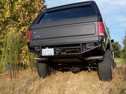 1983 Ford Bronco - Rear view of a dark gray Ford Bronco with a custom bumper and tow hitch, parked outdoors.