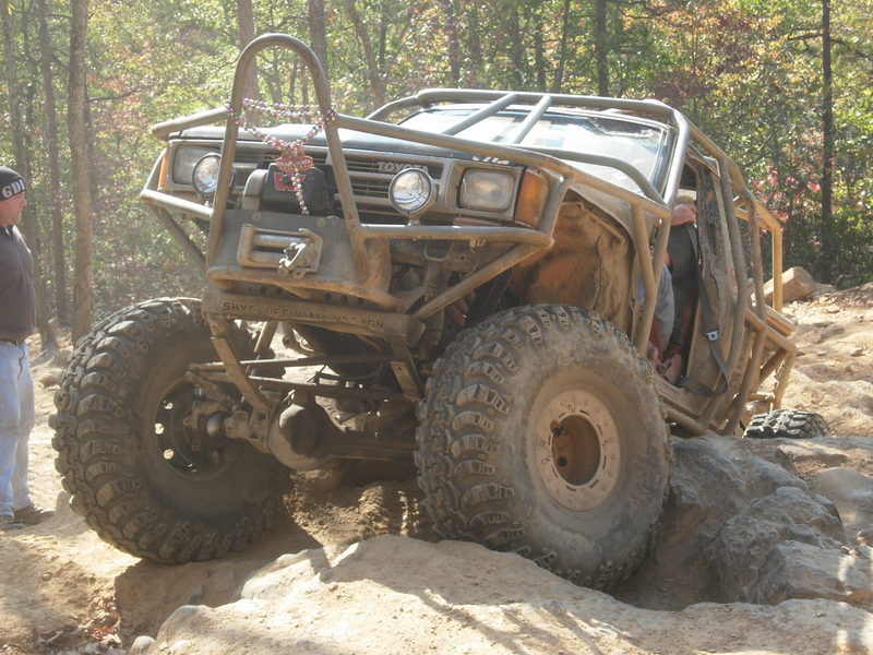 Modified Toyota 4Runner with roll cage, large tires, and winch, on rocky terrain