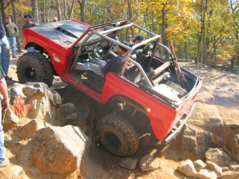 1978 Ford Bronco - This modified off-road vehicle is tackling a challenging rocky trail with onlookers present.