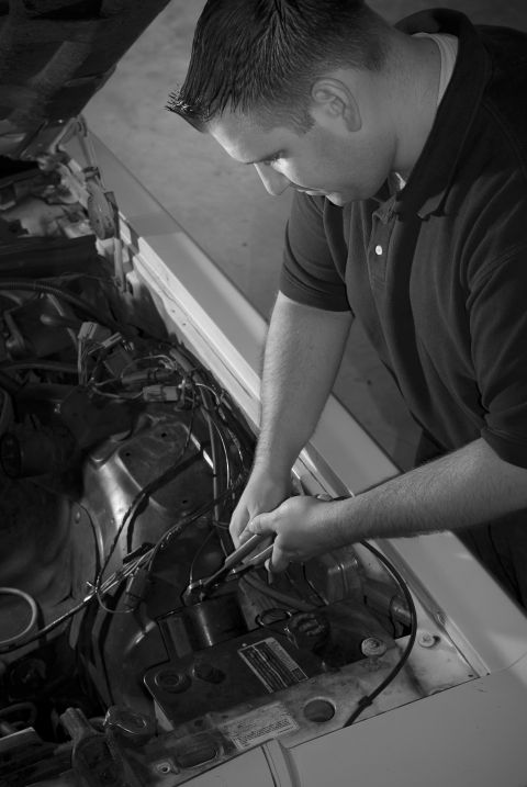 1985 Ford LTD Crown Victoria - Mechanic works on the engine of a car, focusing on electrical wiring.