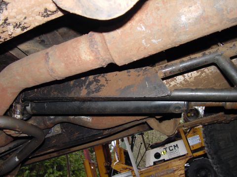 1979 Ford Bronco - The underside of a vehicle shows exhaust pipes and structural components, with a forklift visible in the background.