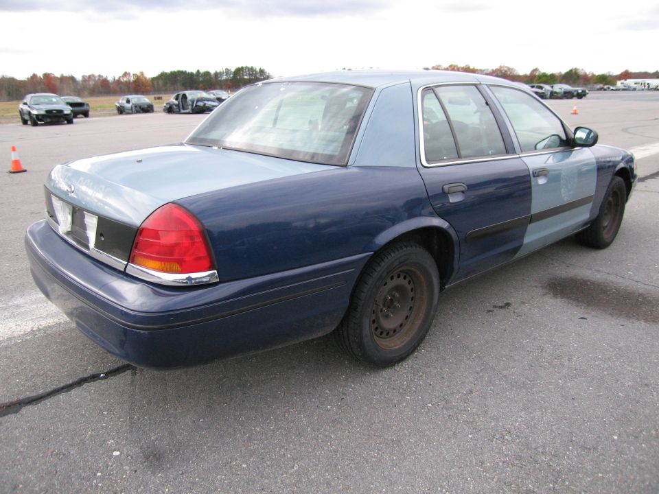 Rear quarter view of a blue and light blue Ford Crown Victoria with steel wheels