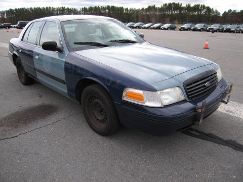 1991 Ford LTD Crown Victoria - A two-tone Ford Crown Victoria, likely a former police vehicle, sits parked on asphalt.