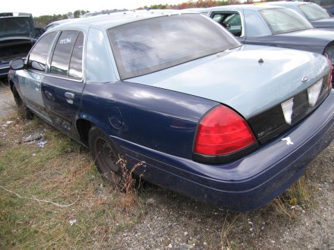 1991 Ford LTD Crown Victoria - This Ford Crown Victoria appears to be from the early 2000s, not a 1991 model, and is parked in a junkyard.