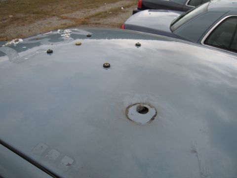 1991 Ford LTD Crown Victoria - Close-up of a car's hood showing damage and mounting hardware, with another vehicle in the background.