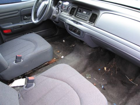 1991 Ford LTD Crown Victoria - The interior of a 1991 Ford Crown Victoria LTD is visible, with worn seats and a cluttered floor.