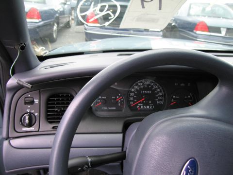 1991 Ford LTD Crown Victoria - The dashboard of a Ford Crown Victoria displays the odometer reading and gear selection, with other vehicles parked nearby.