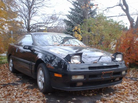 1996 Ford Probe - Front view of a black 1996 Ford Probe with its pop-up headlights partially raised.