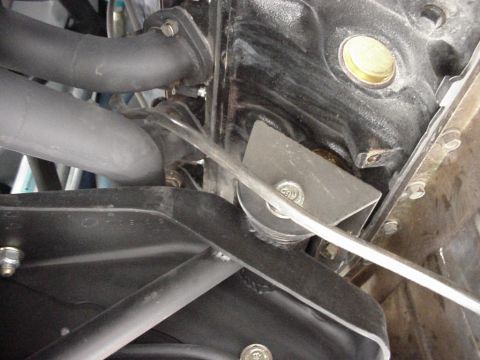 1984 Ford Bronco - Close-up view of engine components, including exhaust pipes and a metal bracket.