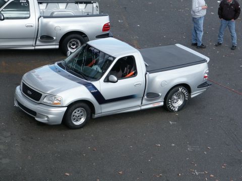 2001 Mercury Grand Marquis - Two silver pickup trucks are parked on asphalt, with two people standing in the background.