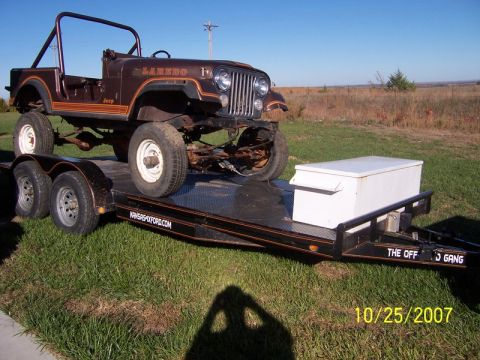 1995 Ford Bronco - A brown Jeep CJ-7 Laredo is loaded onto a trailer, ready for transport.