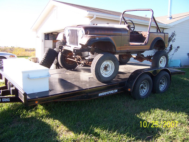 Brown Jeep CJ-5 on a trailer with spare tires and a toolbox