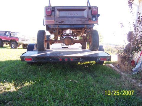 1995 Ford Bronco - A Jeep is loaded onto a trailer, with another vehicle visible in the distance.