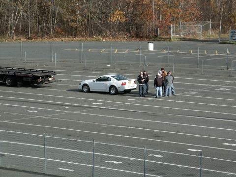 2001 Mercury Grand Marquis - A white Ford Mustang is parked in a lot, with a tow truck and several people nearby.