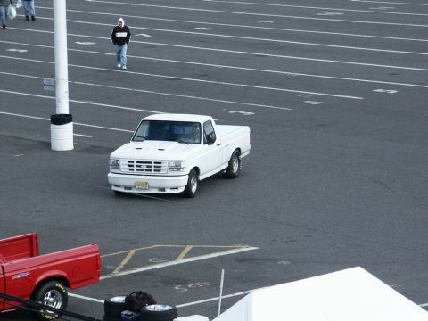 2001 Mercury Grand Marquis - A white 1992 Ford F-150 pickup truck is seen from an elevated perspective on a paved surface with lane markings.