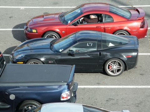 2001 Mercury Grand Marquis - A black Chevrolet Corvette is parked next to a red Ford Mustang and a blue pickup truck.
