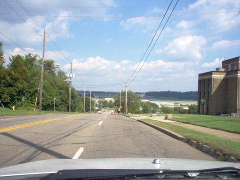 1970 Ford Ranchero - View from a vehicle driving down a road towards a distant body of water under a partly cloudy sky.
