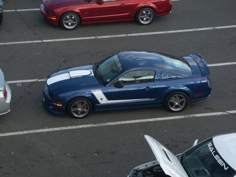 2001 Mercury Grand Marquis - A blue Ford Mustang with racing stripes is parked on a track next to other vehicles.