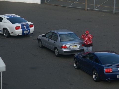 2001 Mercury Grand Marquis - A person stands between a silver sedan and a blue coupe, with a white Mustang in the background.